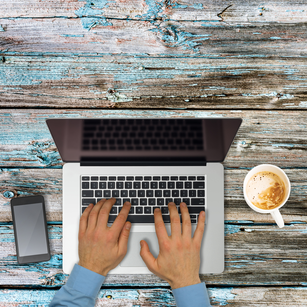 Typing on laptop on wooden table for draft Productivity Commission Report Australia