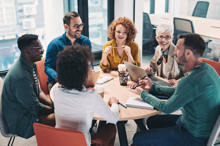 Mixed group of business people sitting around a table and talking about workplace giving