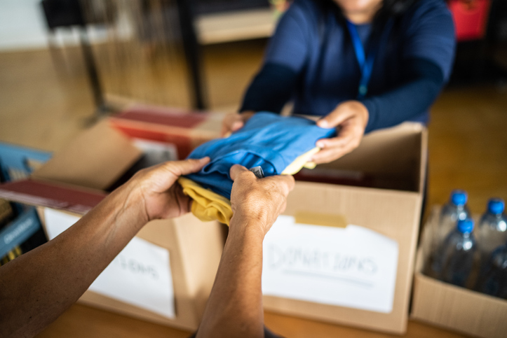 Volunteers hand giving donations to a person at a charity community centre